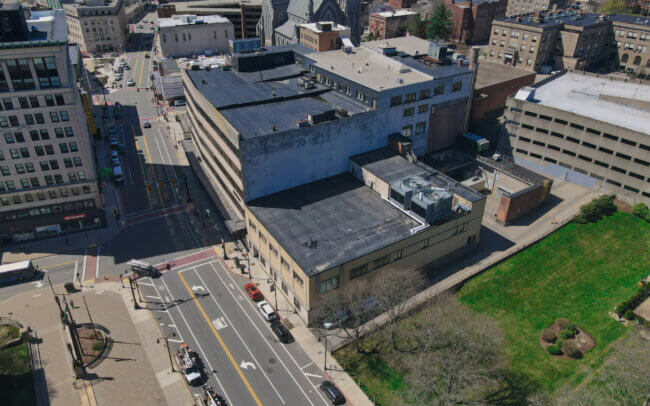 Aerial view of a city skyline with tall buildings, a church spire, and other architectural features visible.